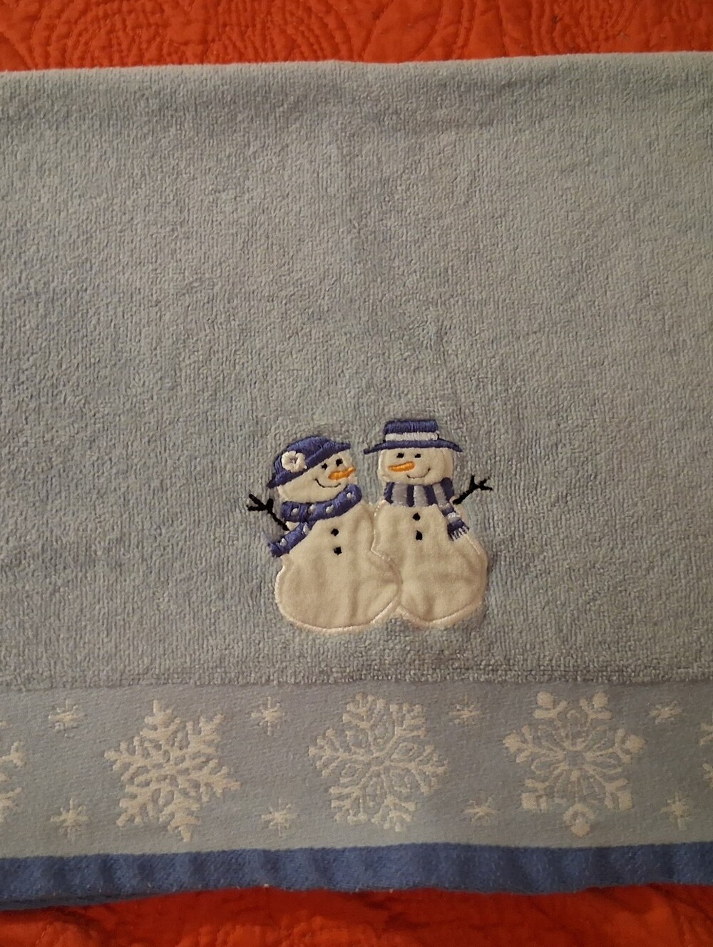 Blue Hand Towel With A Snowman Design On It.